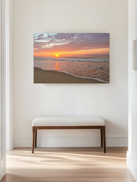 Canvas print of a vibrant sunrise over the Atlantic Ocean on a wall above a wooden bench