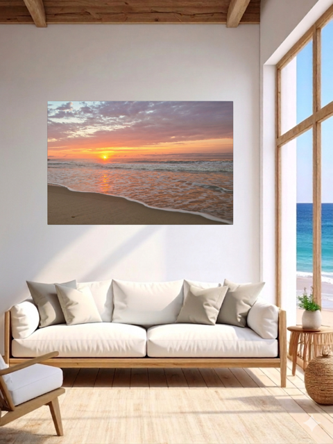 Living room with a canvas print of a vibrant sunrise over the Atlantic Ocean on the wall, white sofa, and large windows.