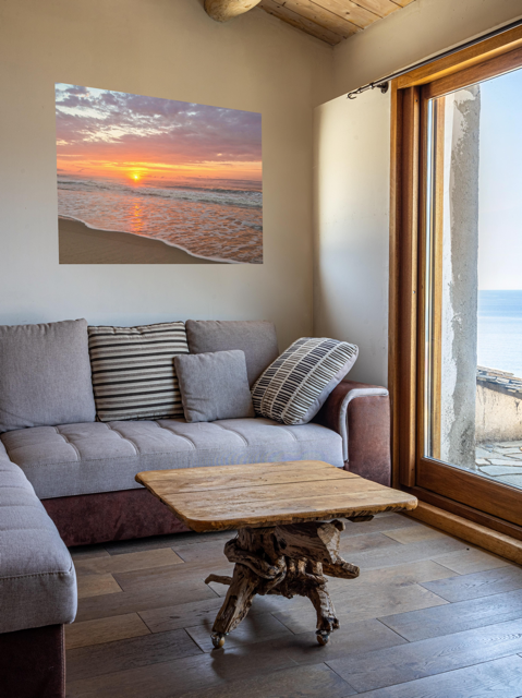 Living room with a gray sofa, wooden coffee table, and a canvas print of a vibrant sunrise over the Atlantic Ocean.