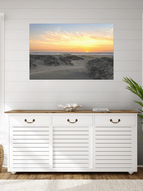 White storage cabinet with wooden top in a room with a canvas print of a beach dunes sunset on the wall.