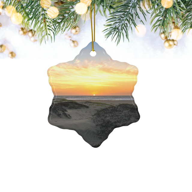 Ceramic Christmas ornament featuring an original photograph of a sunset over coastal sand dunes, hanging from Christmas tree.