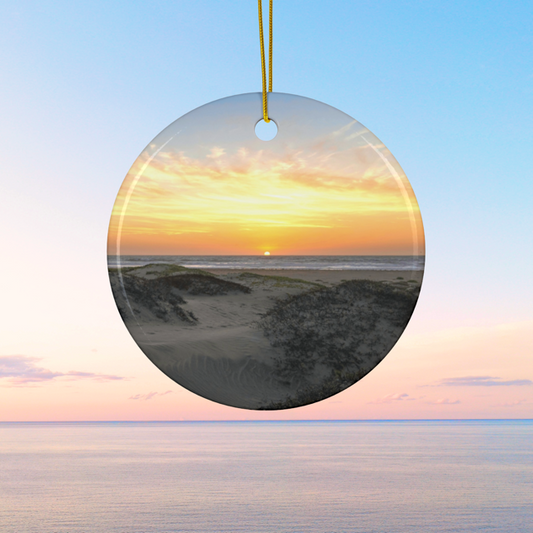Ceramic Christmas ornament featuring an original photograph of a sunset over coastal sand dunes.