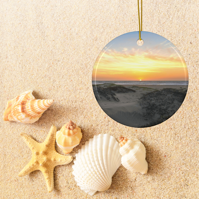 Ceramic Christmas ornament featuring an original photograph of a sunset over coastal sand dunes with beach scene on sand with shells