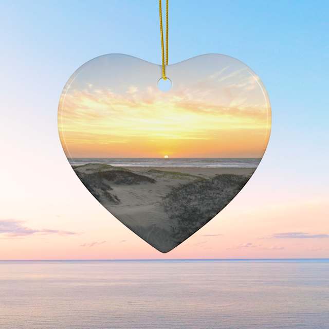 Heart-shaped ceramic Christmas ornament featuring an original photograph of a sunset over coastal sand dunes