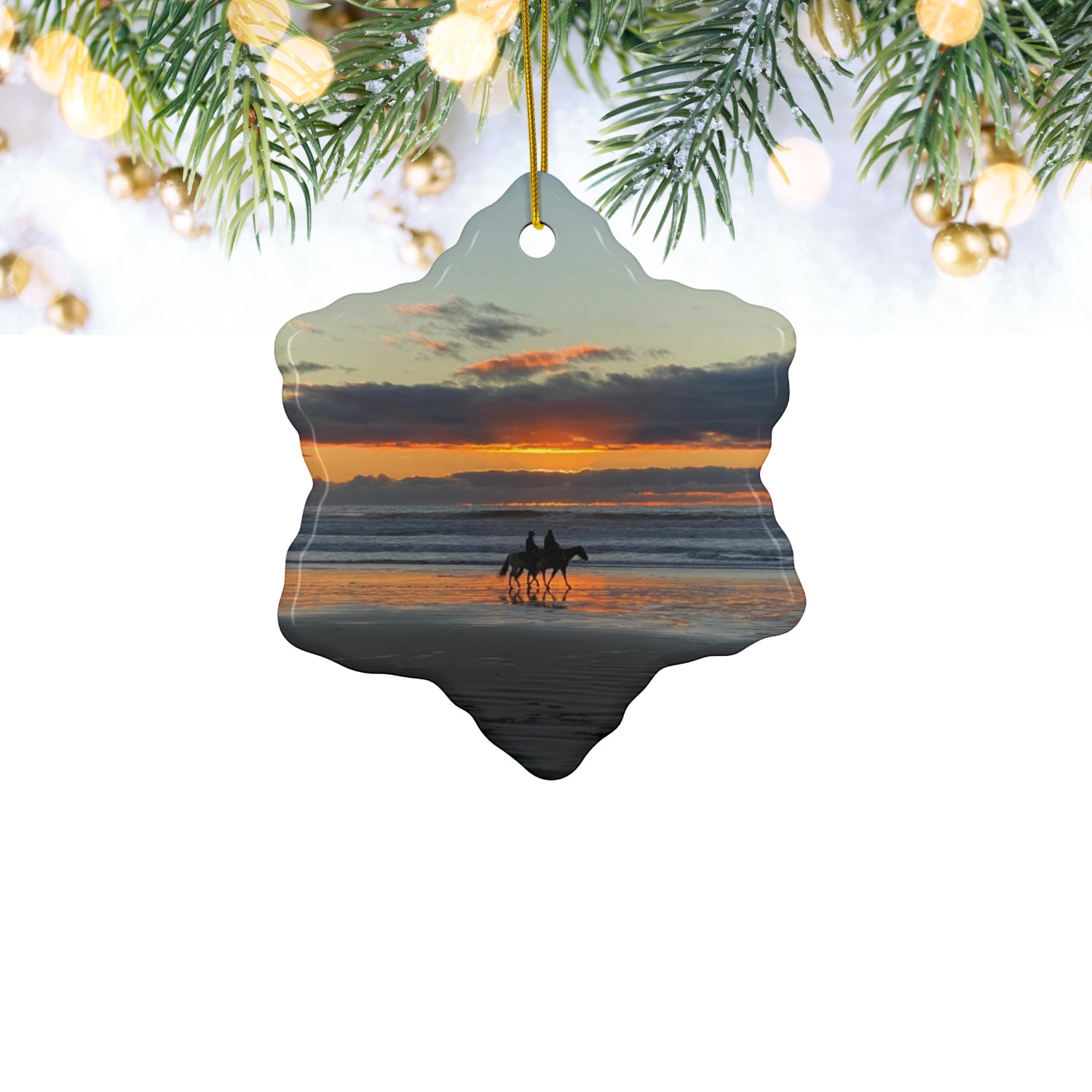 Ceramic holiday ornament featuring a photograph of two horseback riders silhouetted on a beach at sunset with reflections in the wet sand, hanging from Christmas tree.