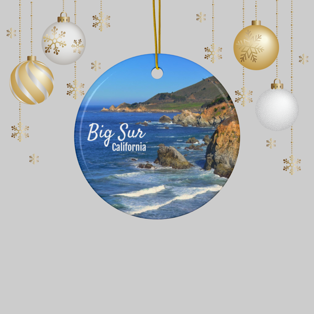 Ceramic Christmas ornament featuring a photograph of the rugged cliffs and deep blue Pacific Ocean along the Big Sur coastline in California, hanging against a light gray background.
