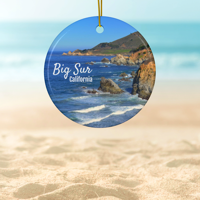 Ceramic Christmas ornament featuring a photograph of the rugged cliffs and deep blue Pacific Ocean along the Big Sur coastline in California, on a beach.