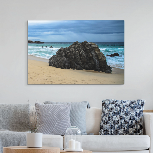Big Sur California coastal rock formation canvas print on a wall above a sofa with decorative pillows.