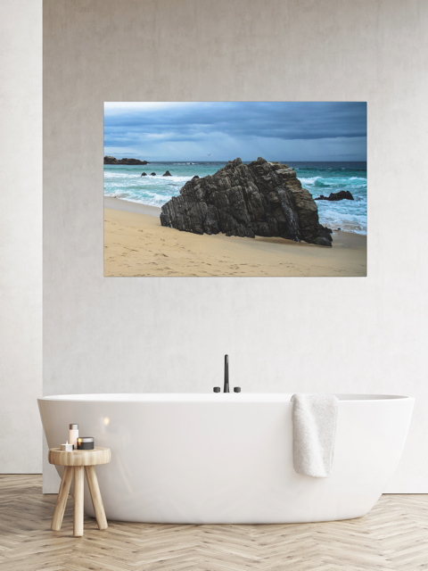 Big Sur California coastal rock formation canvas print on a wall above a white bathtub.