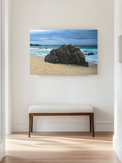 Big Sur California coastal rock formation canvas print on a wall in a room with a bench.