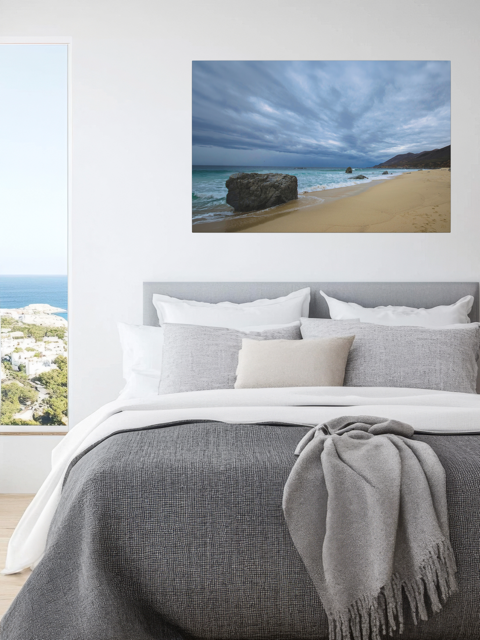 Bedroom with a canvas print of a Big Sur beach with a stormy sky.