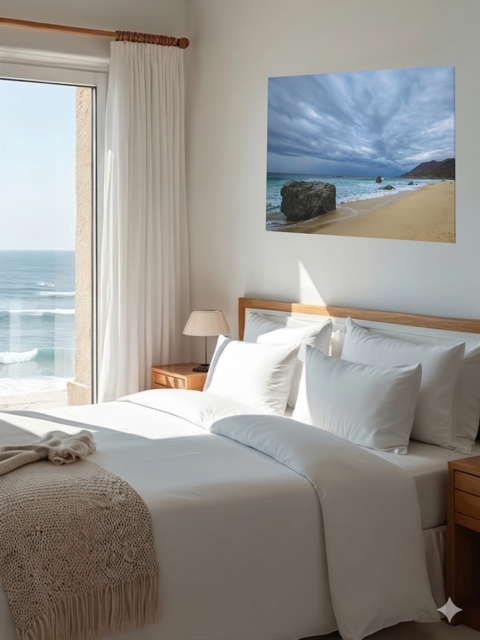 Bedroom with a large bed, ocean view, and a canvas print of a Big Sur beach with a stormy sky on the wall.