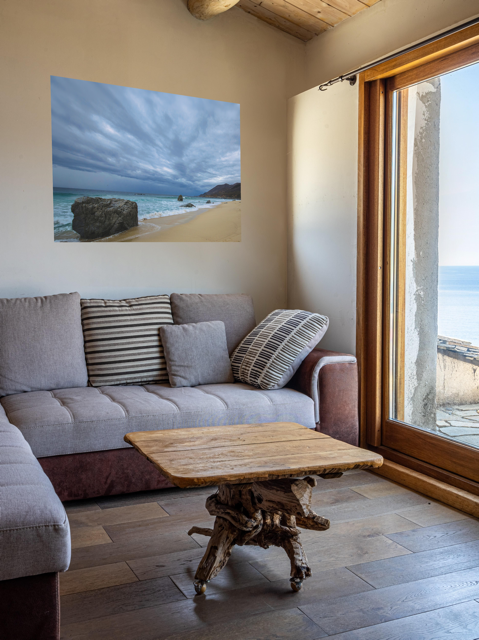 Living room with a gray sofa, wooden coffee table, and a canvas print of a Big Sur beach with a stormy sky.