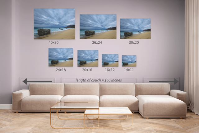 Living room with a beige sectional sofa and canvas prints of a Big Sur beach with a stormy sky with measurements.