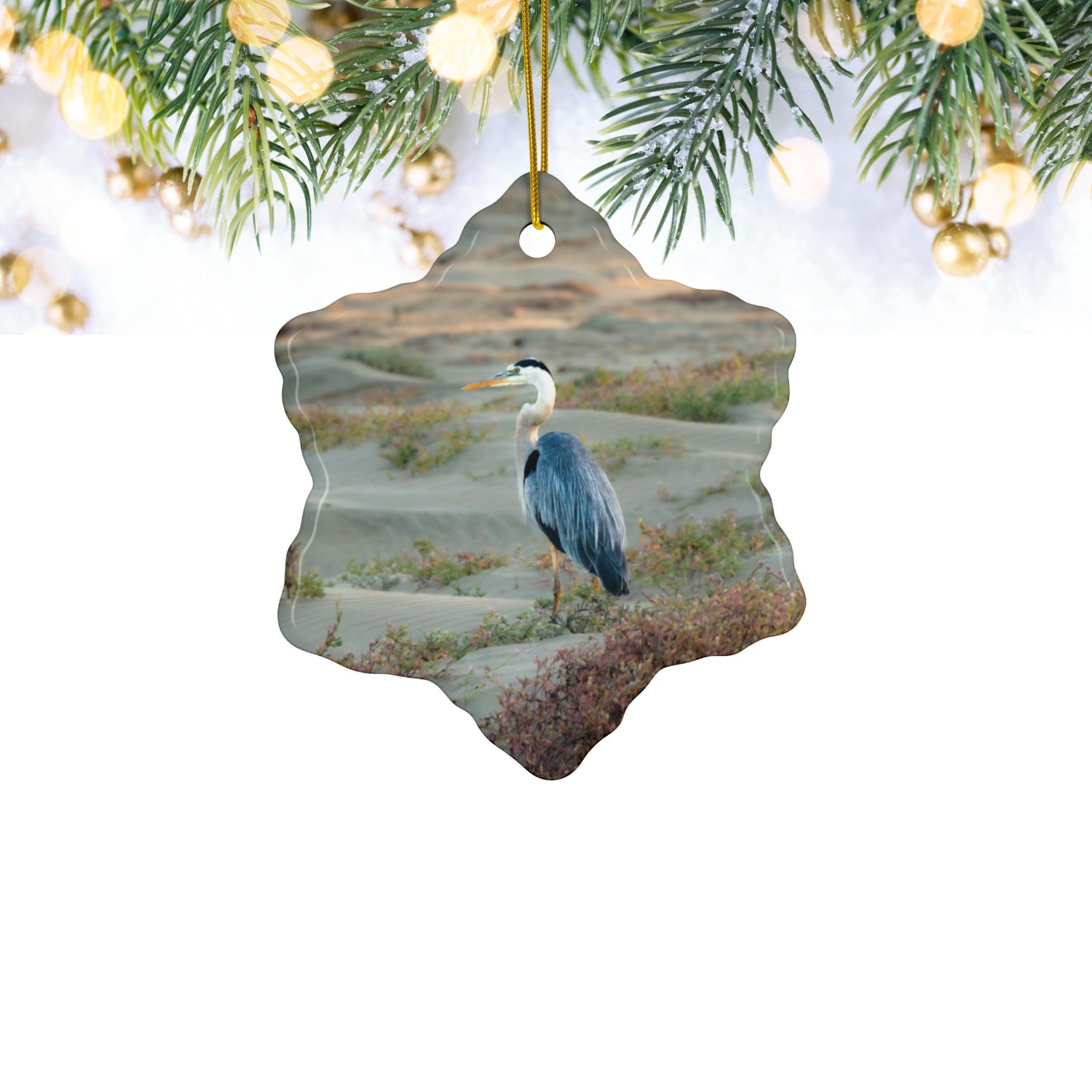 Ceramic holiday ornament featuring a professional photograph of a Great Blue Heron standing among coastal reeds along the Pacific shoreline.