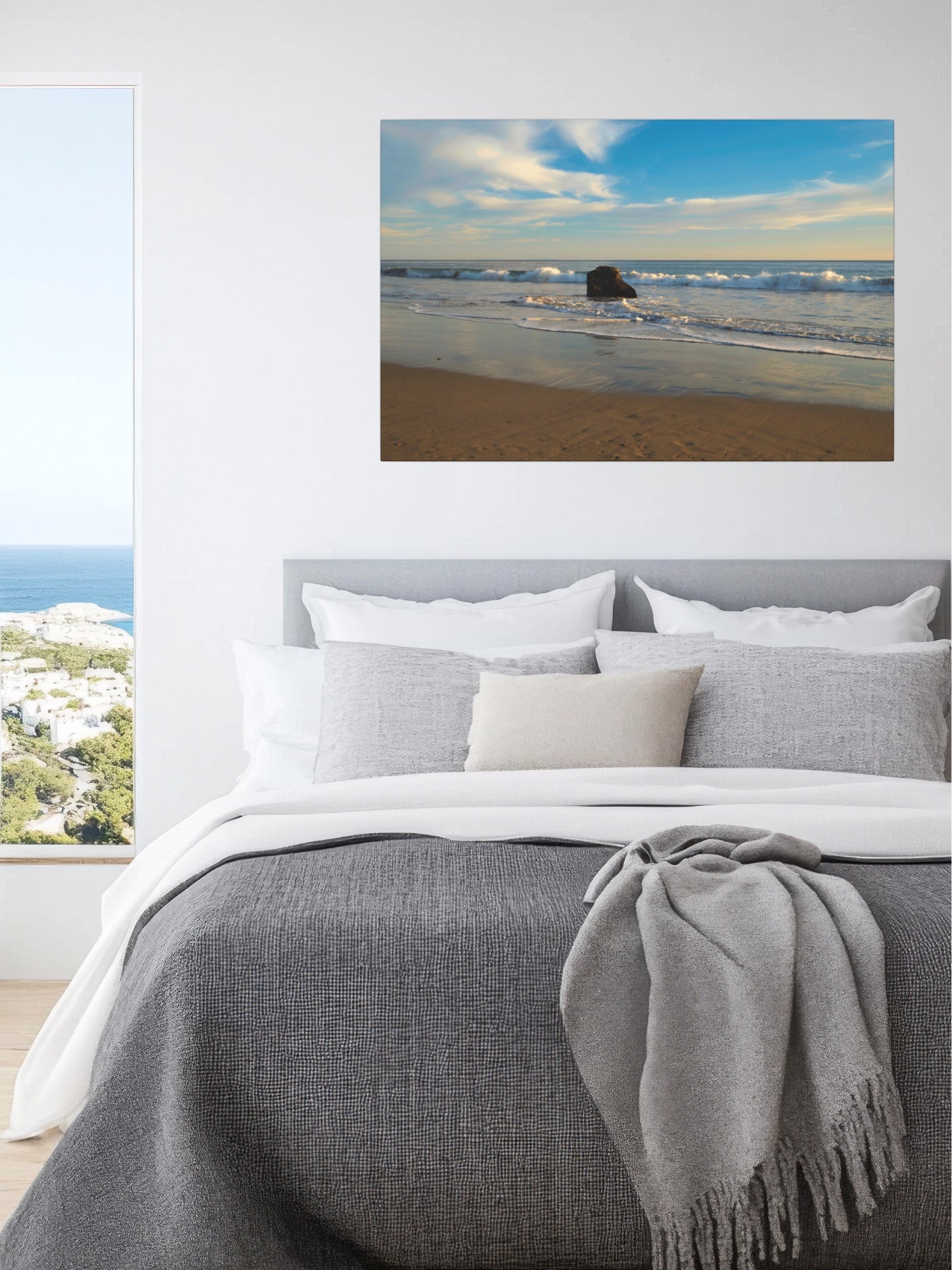 Bedroom with solitary rock on a California beach with ocean wave foam and sky reflection canvas print above the bed.