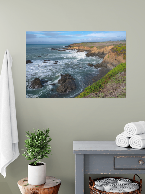 Scenic wall art of a coastal landscape on a gray wall above a cabinet with towels.