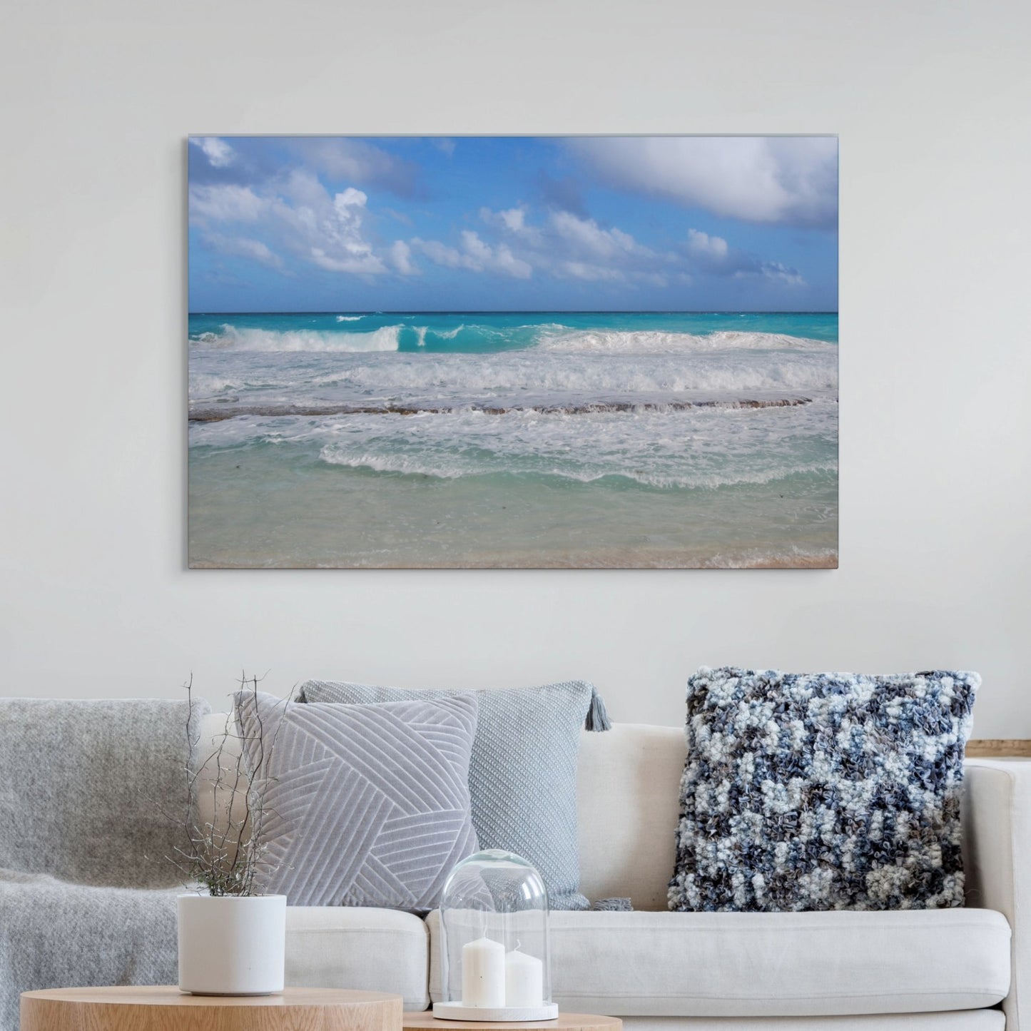 Cancun Caribbean turquoise waves breaking on sand canvas print on a wall above a sofa with decorative pillows.