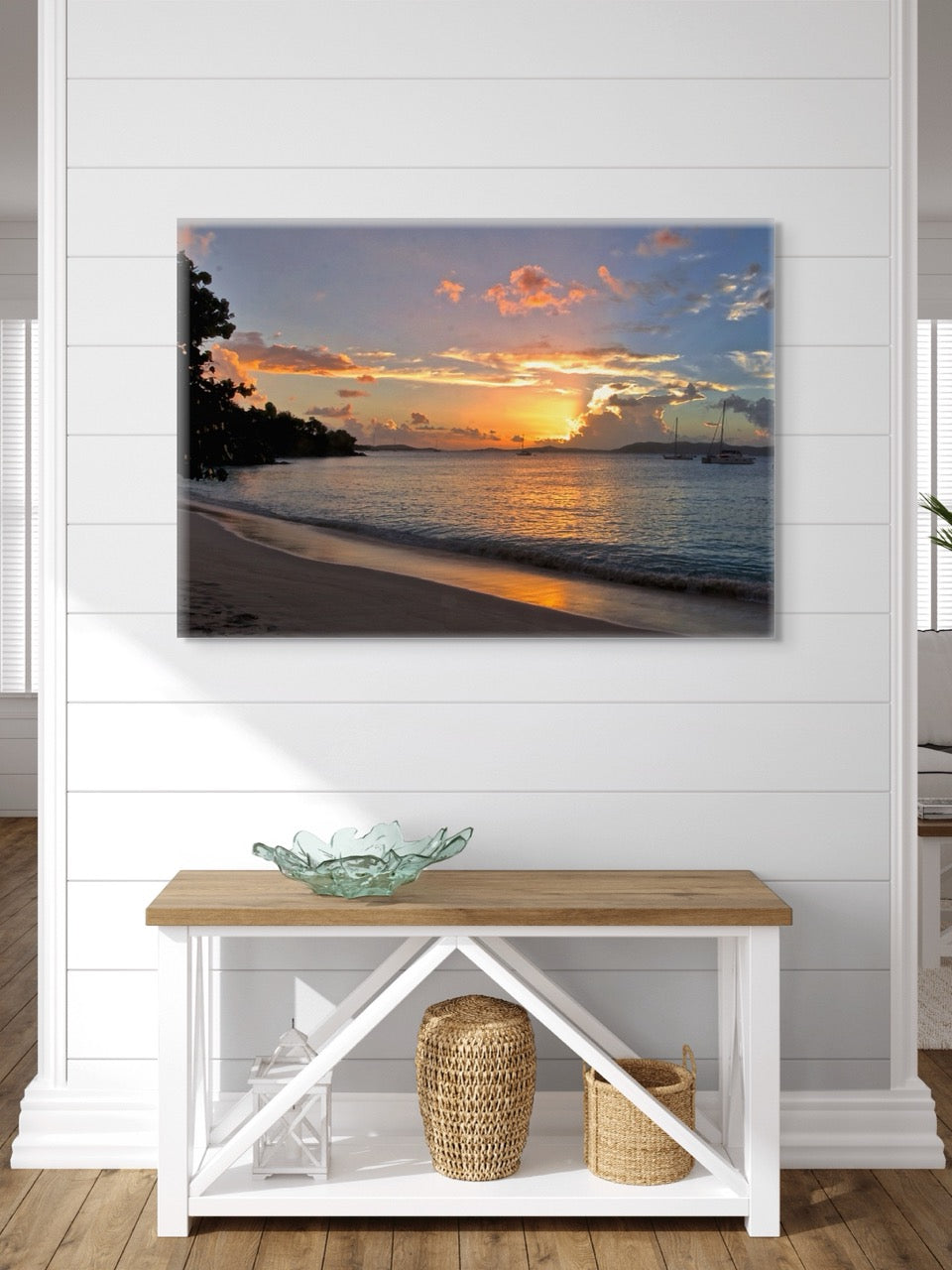 A tropical sunset canvas print  on a wall above a wooden console table with decorative items.