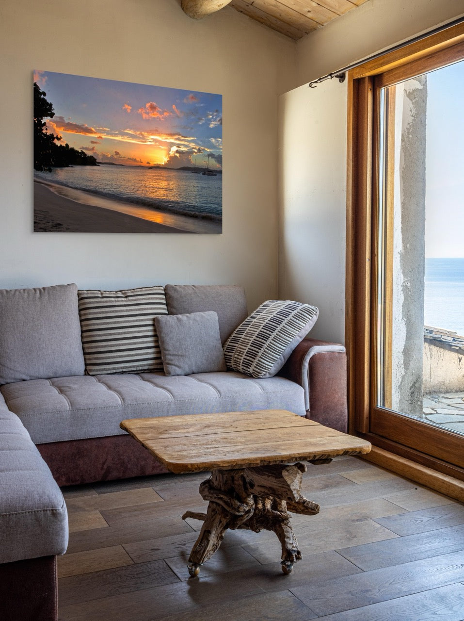 Living room with a gray sofa, wooden coffee table, and a tropical sunset canvas print .
