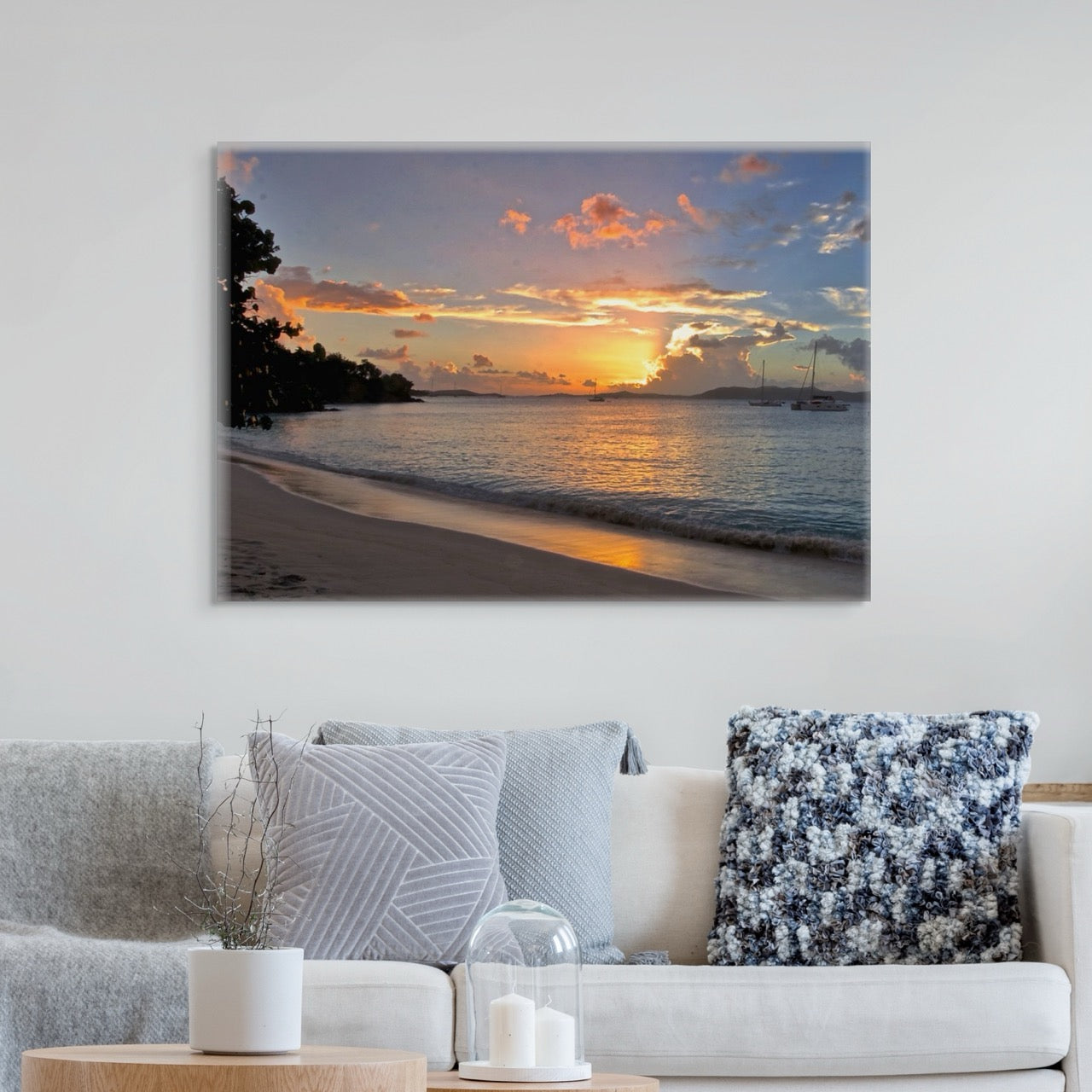 A tropical sunset canvas print  on a wall above a living room sofa with decorative pillows.