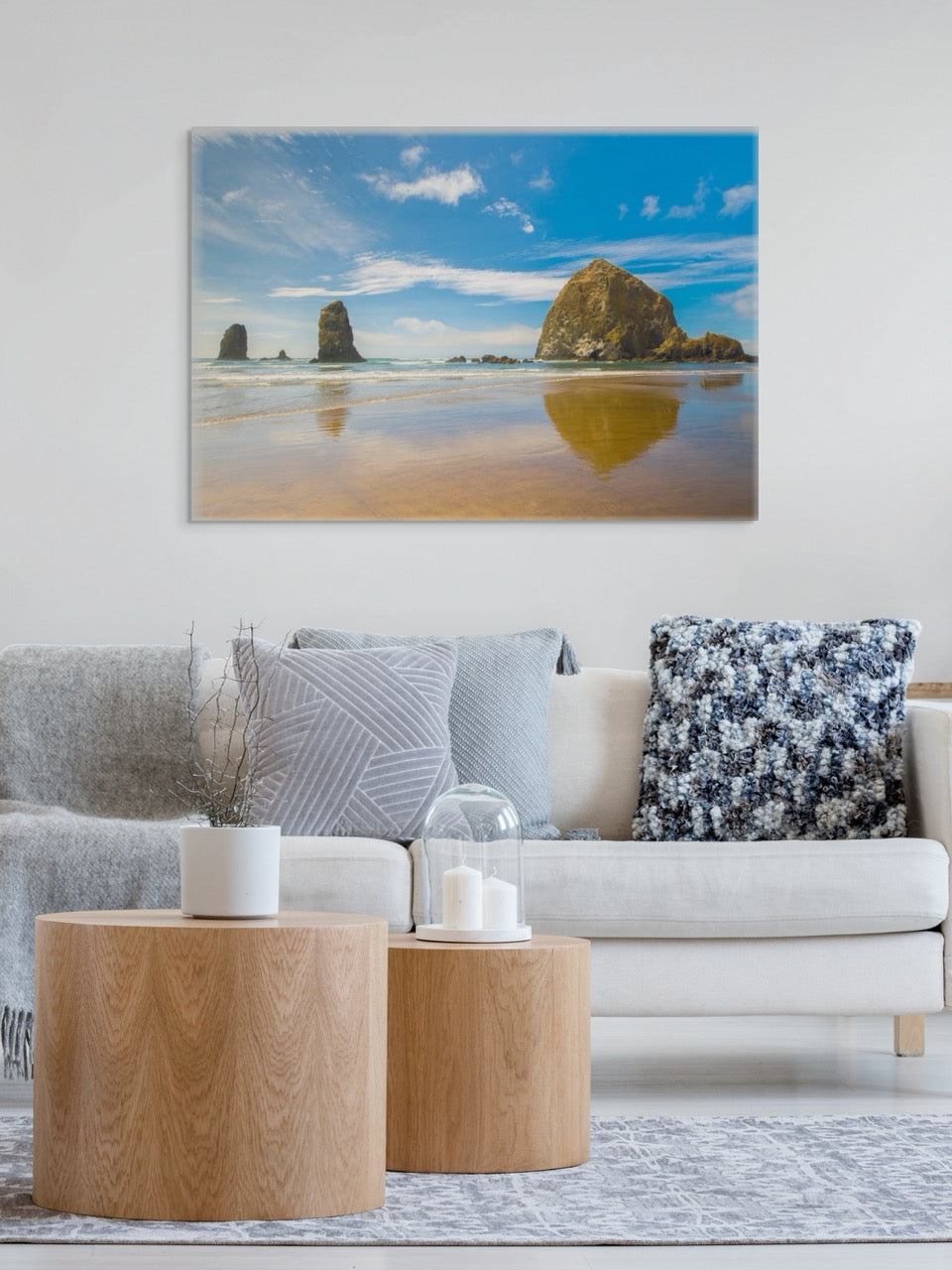 Living room with a large canvas print featuring a view of Haystack Rock and other rock off the coast of Cannon Beach, Oregon on the wall above a sofa.