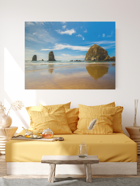 Living room with yellow sofa and a large canvas print featuring a view of Haystack Rock and other rock off the coast of Cannon Beach, Oregon on the wall.
