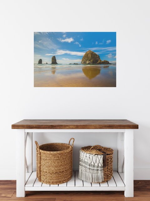 Wooden console table with wicker baskets against a wall with a canvas print featuring a view of Haystack Rock and other rock off the coast of Cannon Beach, Oregon.
