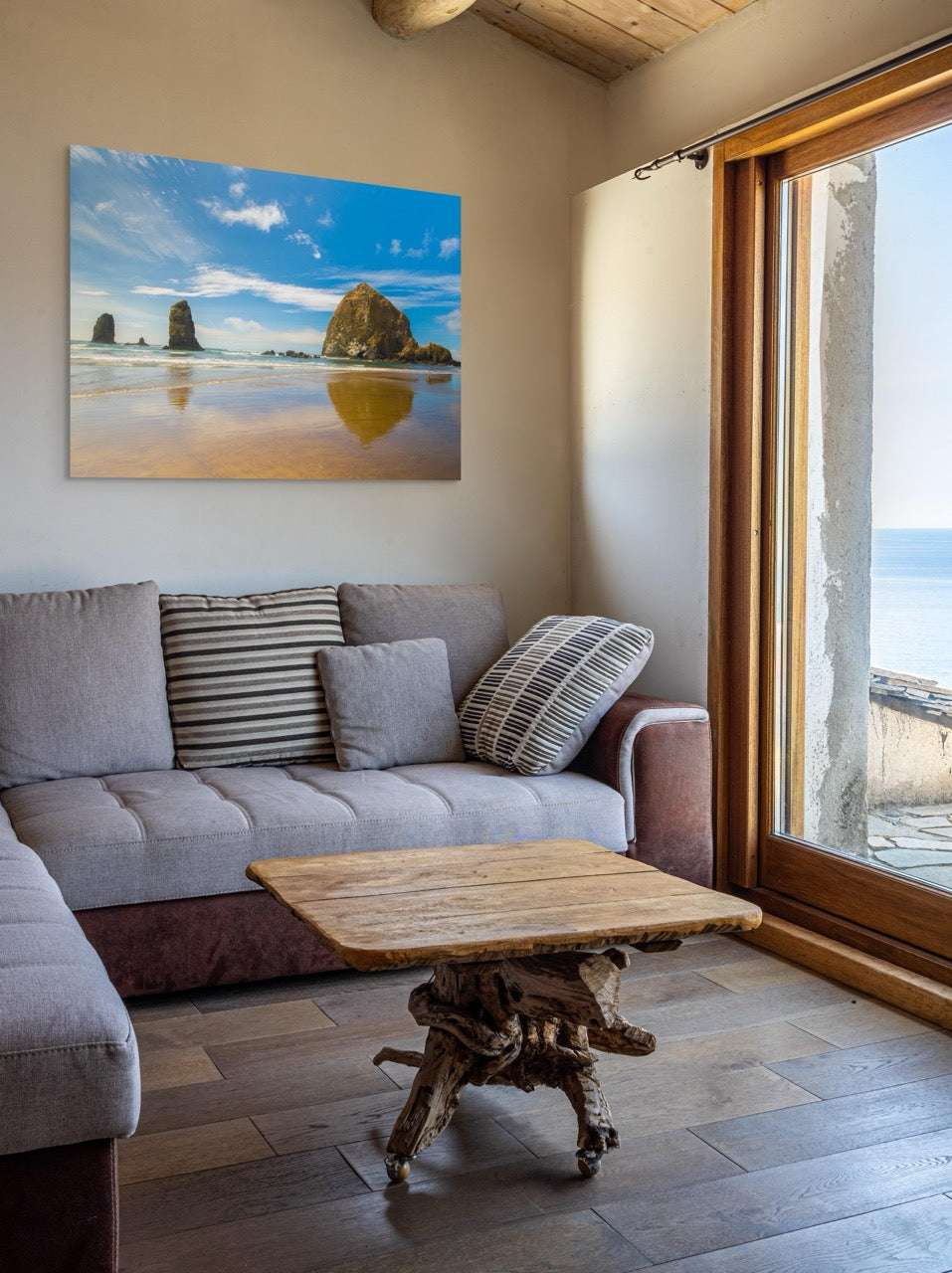 Living room with a gray sofa, wooden coffee table, and a large canvas print featuring a view of Haystack Rock and other rock off the coast of Cannon Beach, Oregon.