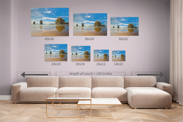 Wall art prints featuring a view of Haystack Rock and other rock off the coast of Cannon Beach, Oregon with corresponding dimensions displayed above a beige sofa.