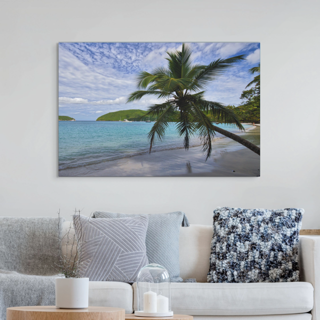 A canvas print of a tropical beach scene on wall above a living room sofa.