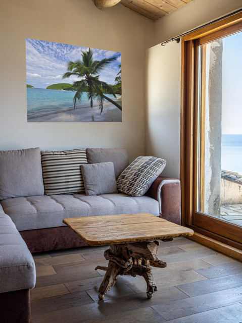 Living room with a gray sofa, wooden coffee table, and a canvas print of a tropical beach scene on the wall.