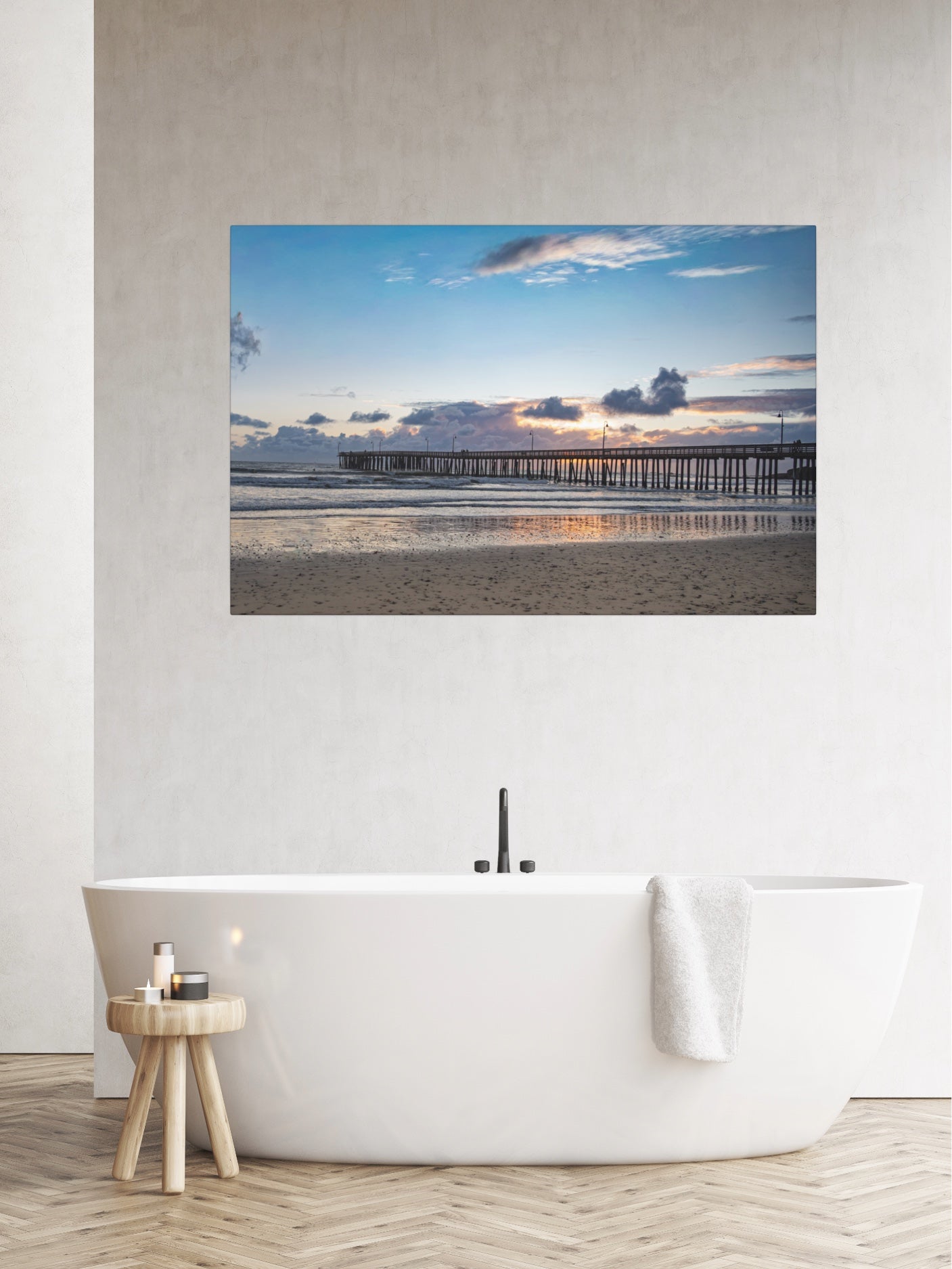 Cayucos Pier sunset canvas print on a wall above a white bathtub in a bathroom.