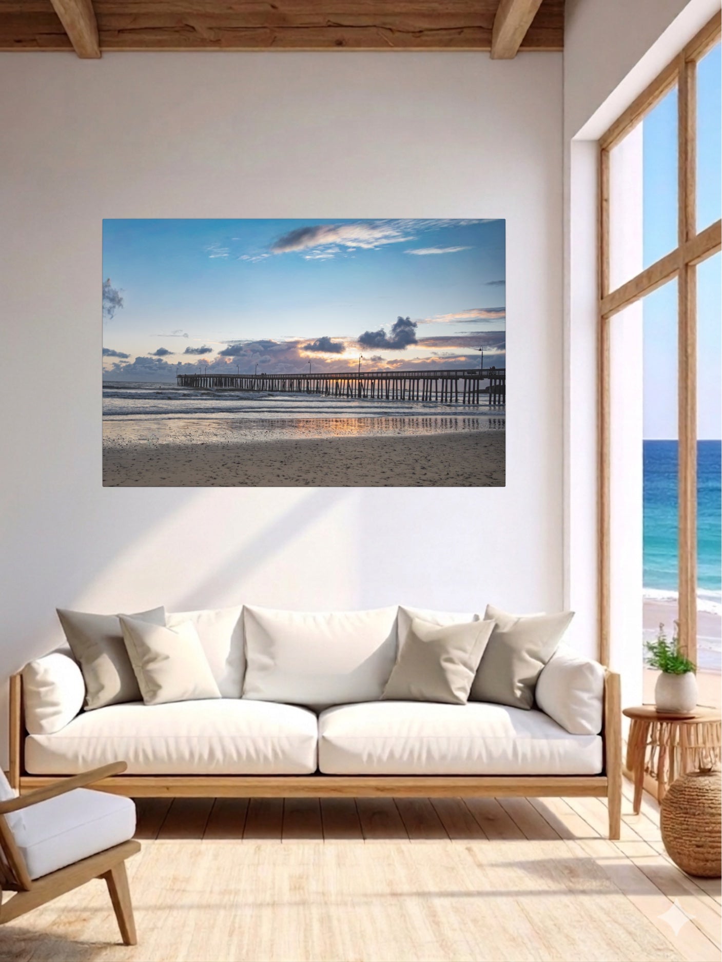 Living room with a Cayucos Pier sunset canvas print on the wall, wooden floor, and white sofa.