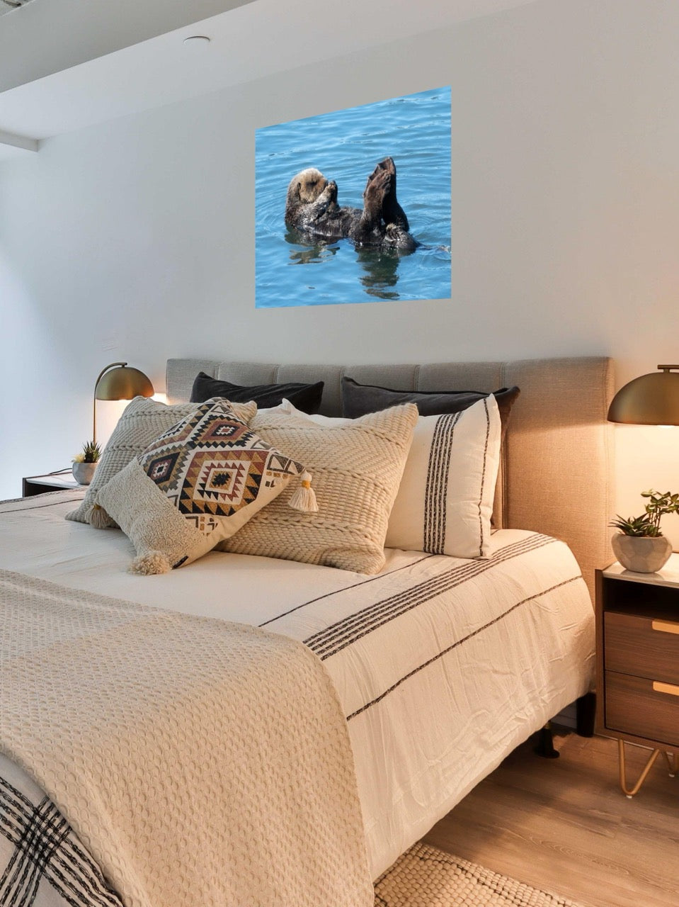 Bedroom with a bed featuring patterned pillows and a wall art of a sea otter in water.