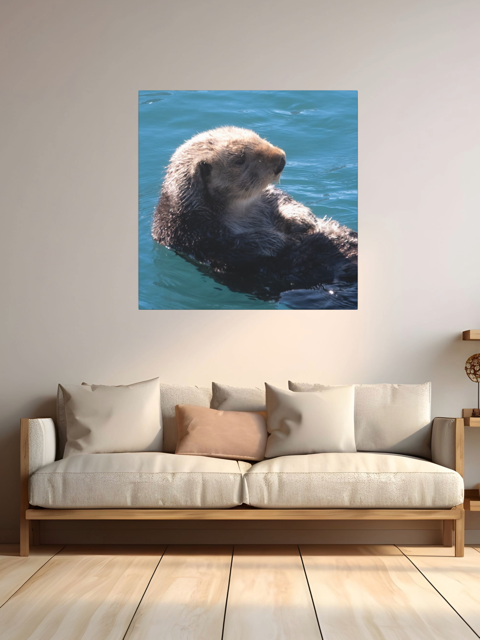 Sofa with a canvas print of a sea otter on a wall in a room.