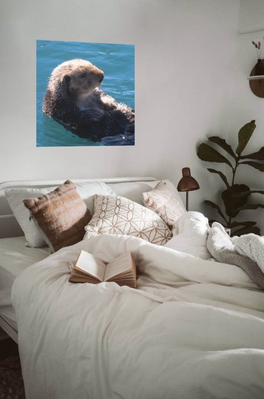Room interior with a bed, pillows, and a canvas print of a sea otter on the wall.