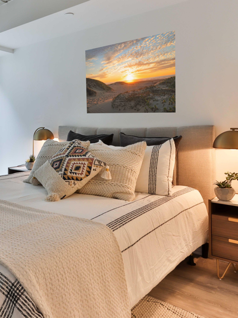 A canvas print of a beach dunes sunset over a bed.