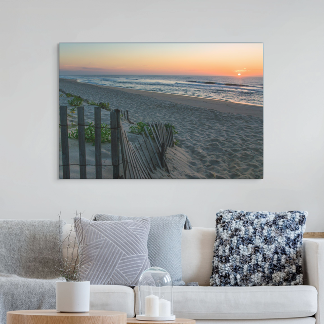 Living room with a canvas print of a coastal sunrise on a sandy beach with a weathered wooden fence on the wall