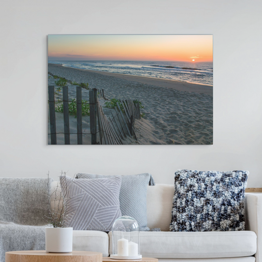 Living room with a canvas print of a coastal sunrise on a sandy beach with a weathered wooden fence on the wall
