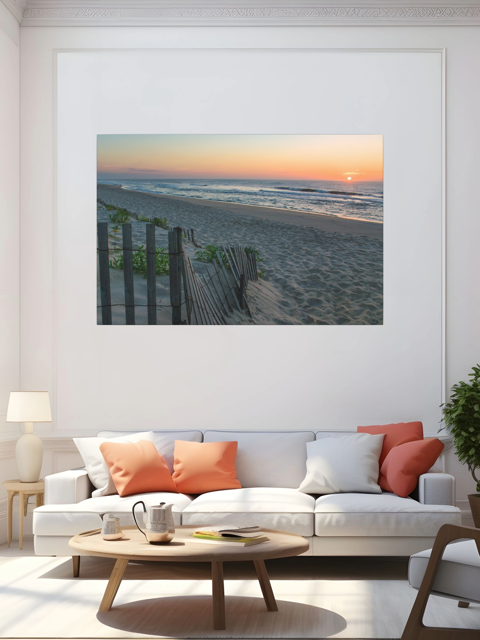 Living room with a white sofa, wooden coffee table, and a canvas print of a coastal sunrise on a sandy beach with a weathered wooden fence on the wall.
