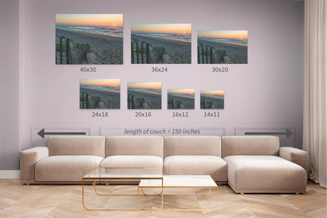 Living room with a beige sectional sofa and a canvas print of a coastal sunrise on a sandy beach with a weathered wooden fence displayed in seven different sizes.