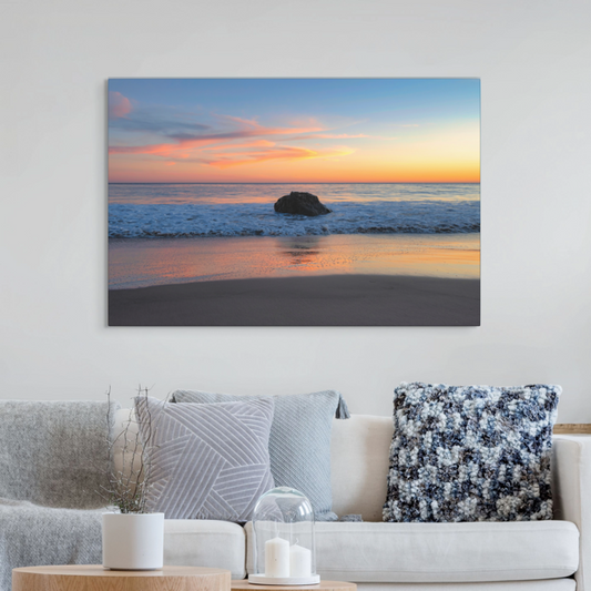 Beach sunset canvas print on a wall above a sofa with decorative pillows.