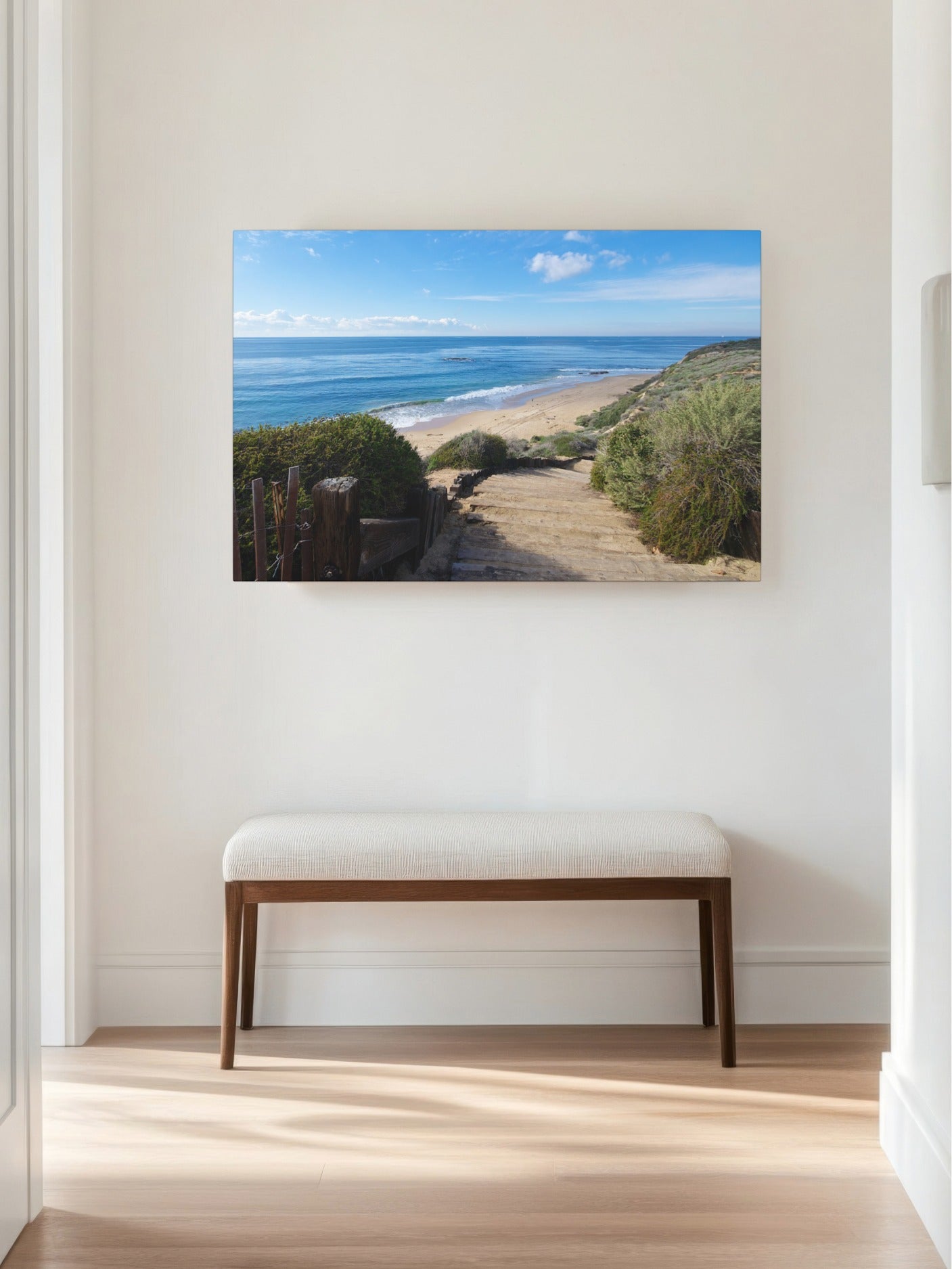 Canvas print of the wooden stairs leading to Crystal Cove State Beach in Orange County California on a wall above a white bench in a room.