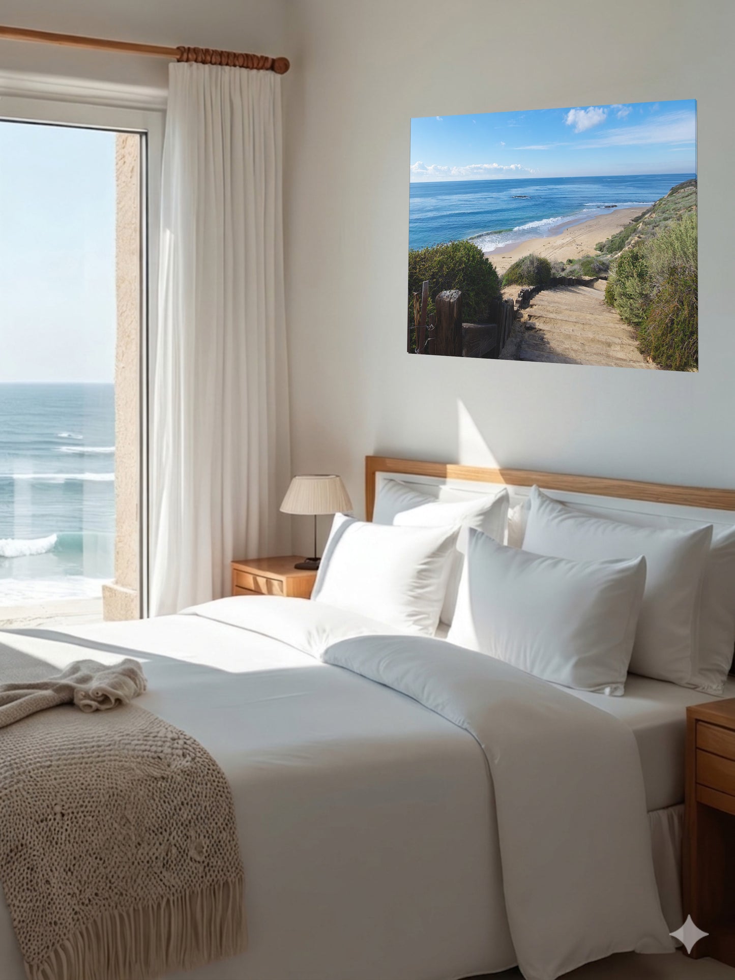 Bedroom with a large bed, ocean view, and a canvas print of the wooden stairs leading to Crystal Cove State Beach in Orange County California.