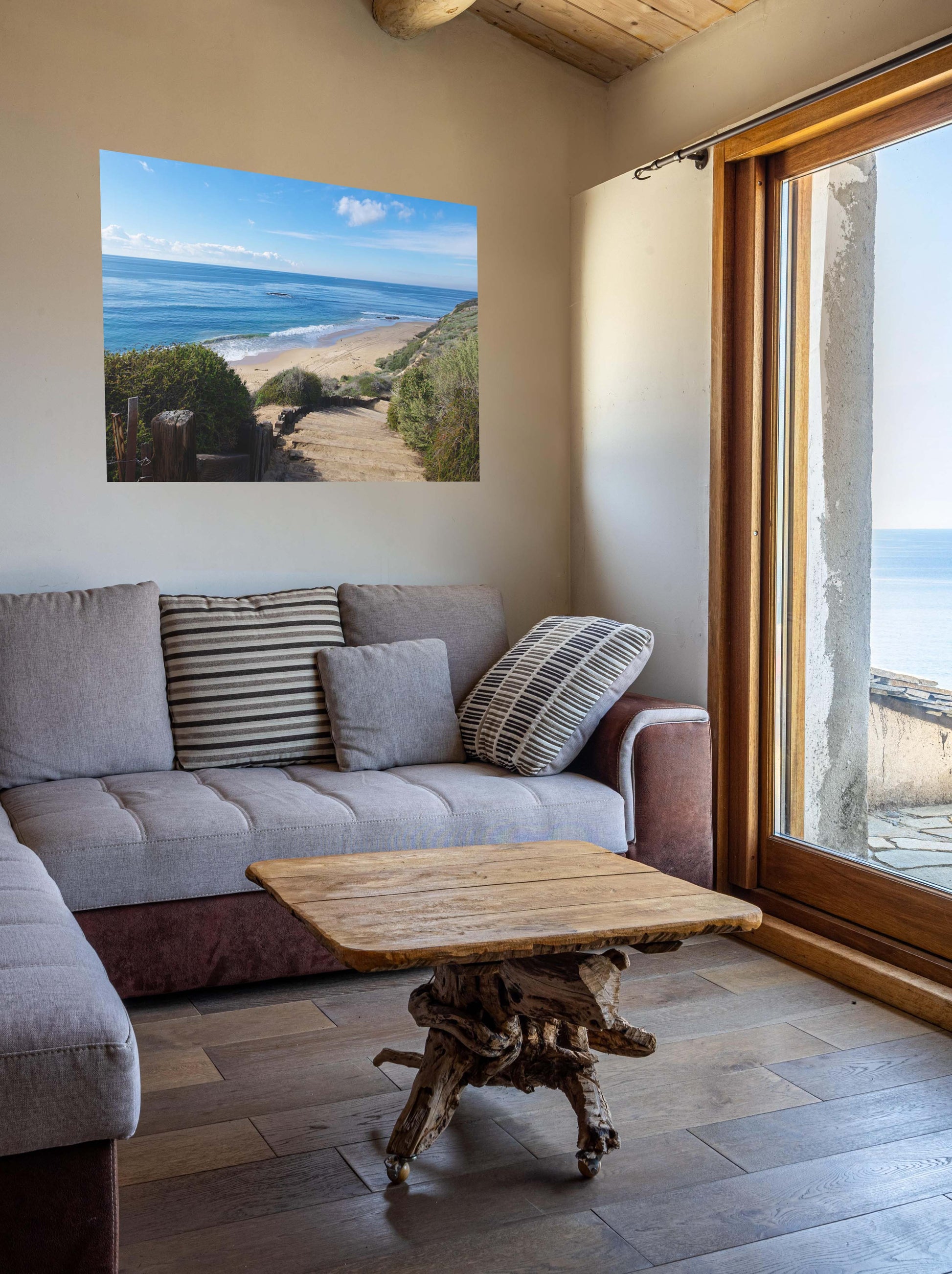 Living room with a gray sofa, wooden coffee table, and a canvas print of the wooden stairs leading to Crystal Cove State Beach in Orange County California.
