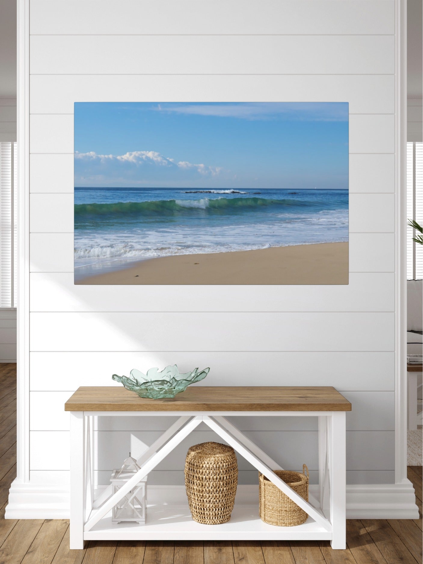 Crystal Cove State Beach breaking wave with translucent green water canvas print on a wall above a wooden bench with a glass bowl and woven baskets.