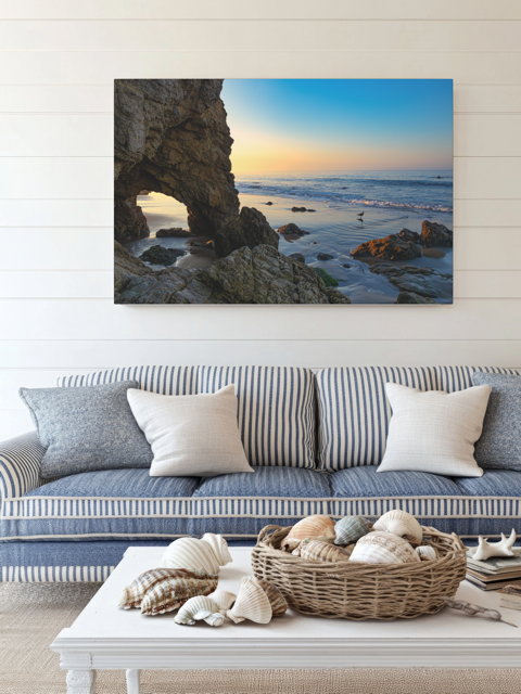 Living room with a couch, coffee table, and a canvas print of a sea cave at sunrise in Malibu.