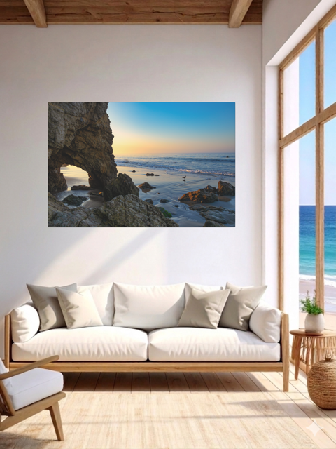 Living room with a canvas print of a sea cave at sunrise in Malibu above a white sofa.