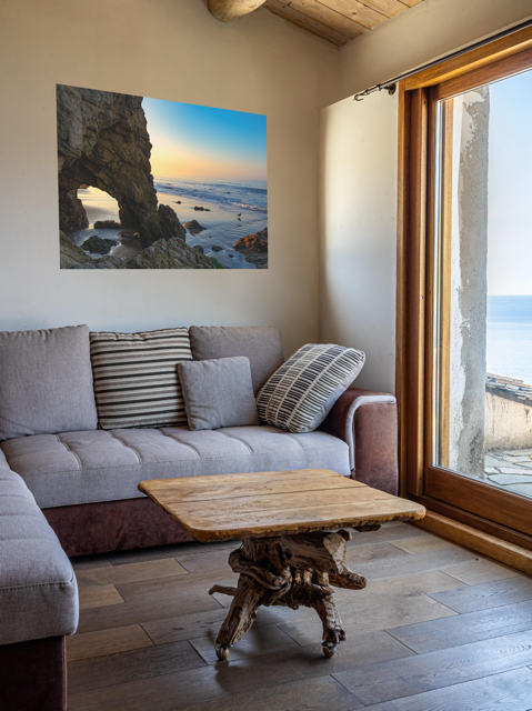 Living room with a gray sofa, wooden coffee table, and a canvas print of a sea cave at sunrise in Malibu.